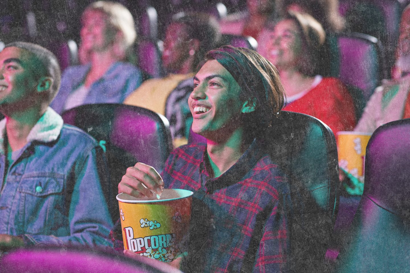 Young person laughing while watching a film at the cinema